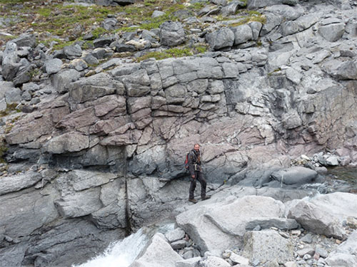 Gregor Markl for scale on magmatic layering in kakortokites, Ilímaussaq. Black layers are arfvedsonite-rich, red layers eudialyte-rich, and grey layers are alkali feldspar and nepheline-rich.